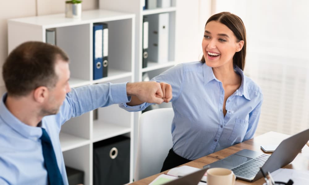 The image displays two coworkers celebrating.  