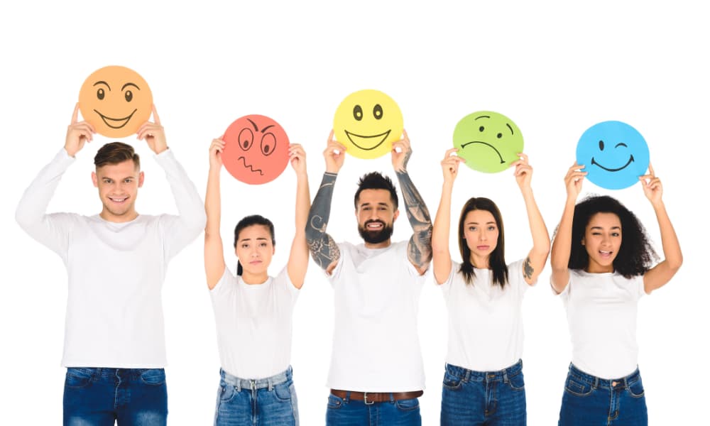 A line of people dressed in jeans and t-shirts hold up signs that indicate their level of satisfaction, from a frowny face to a smile. 